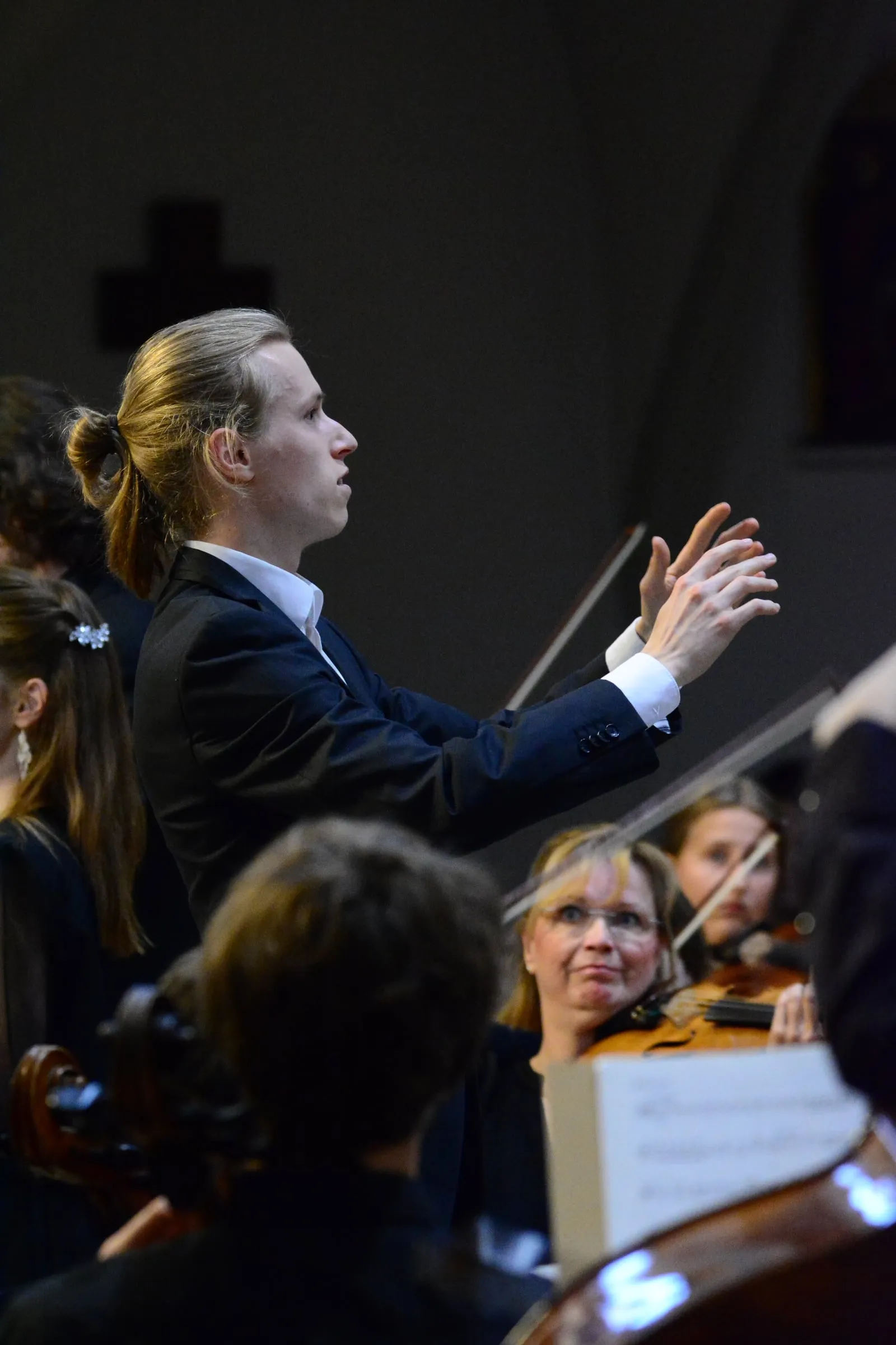 Niklas Lustig dirigiert, beide Hände erhoben, vor Orchester und Chor